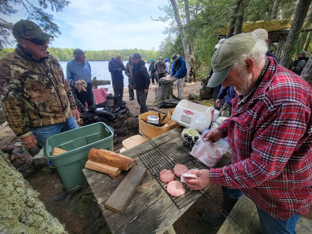 maine guide prepares meat to be grilled for a group of paddlers