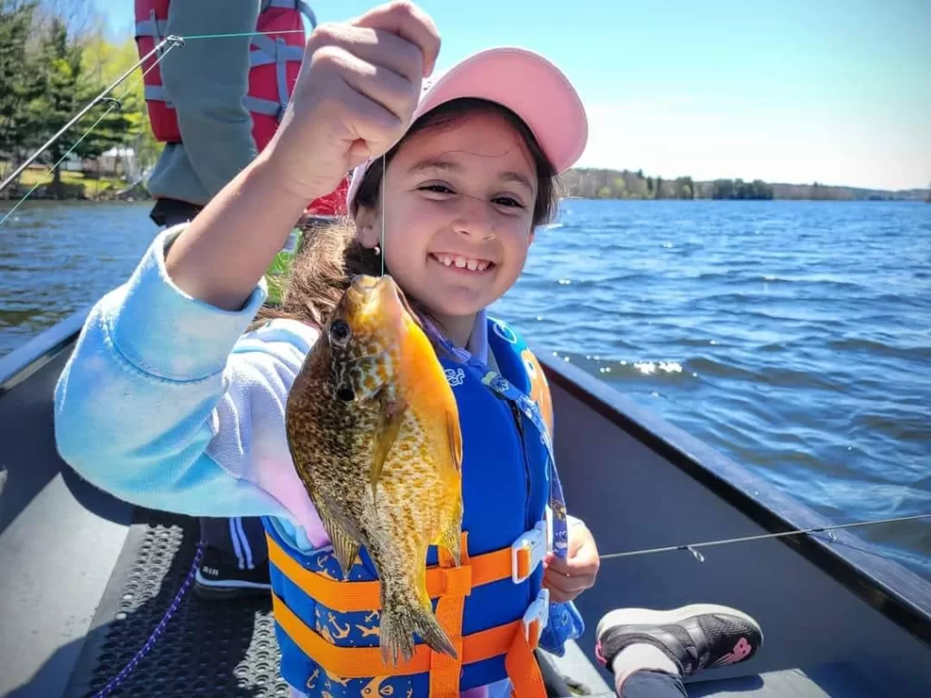 young girl in a boat holding a fish she caught