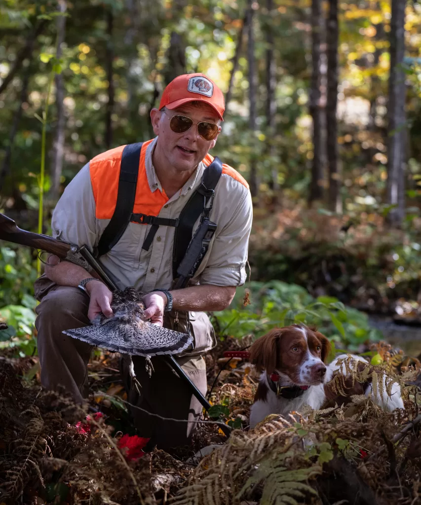 hunter posing with bird and dog after a successful bird hunt