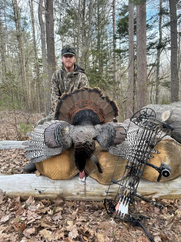 maine hunter posing with large turkey after a successful hunt