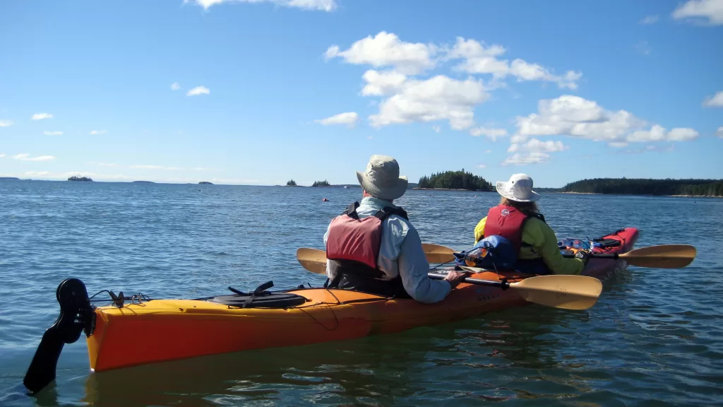 two maine sea kayakers paddling a tandem kayak on a sunny day
