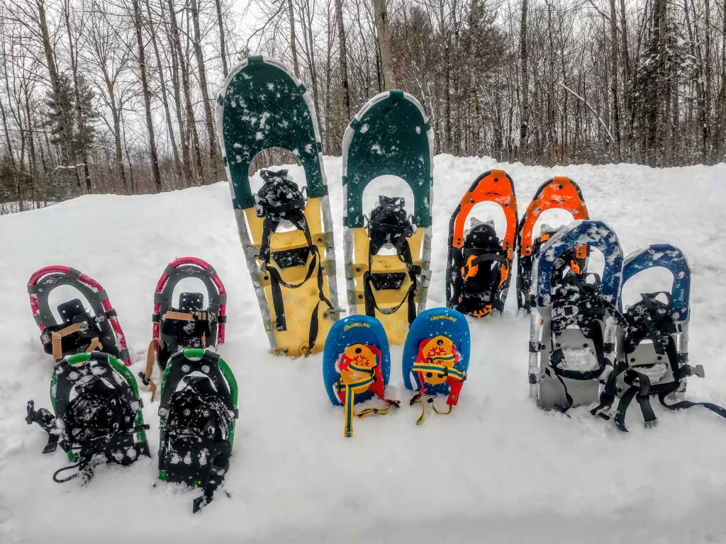 various pairs of snowshoes sticking out of a deep snowbank