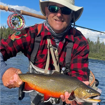 A fisherman holding a brook trout they caught
