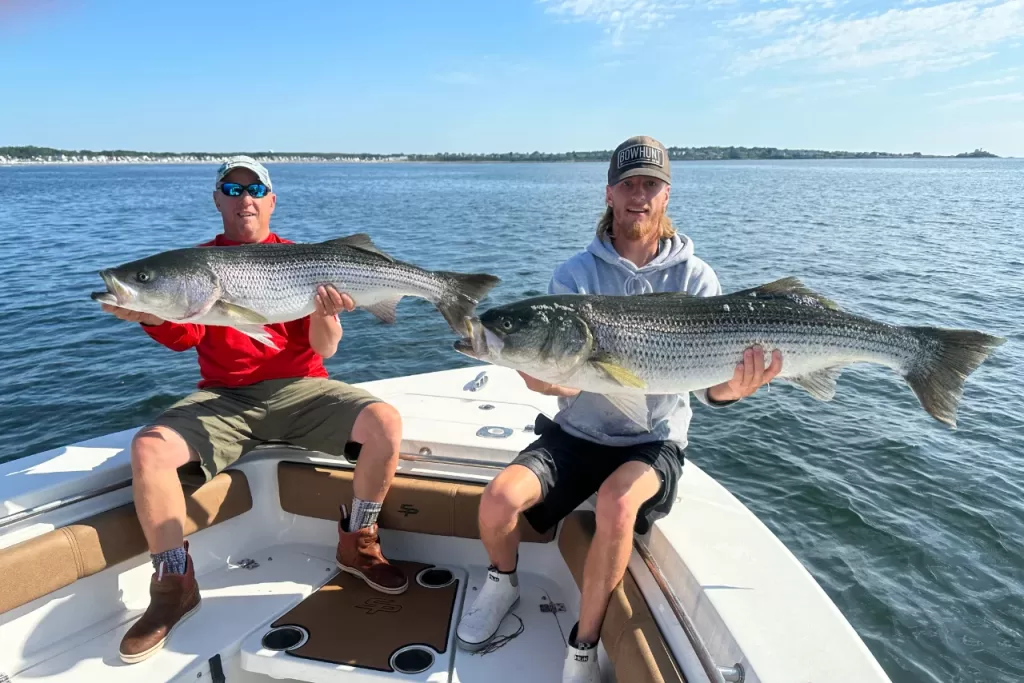 two people on a boat holding huge fish